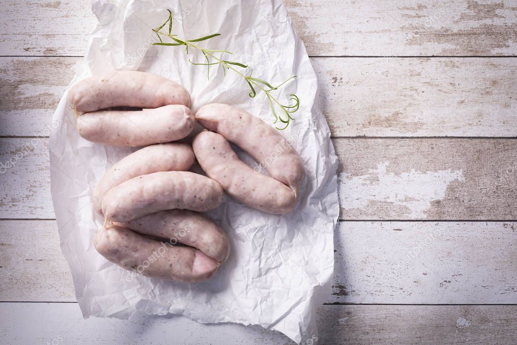 White sausage. Traditional raw white sausage on a wooden background.