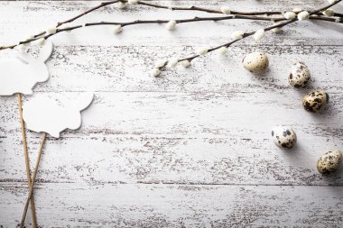 Ahşap bir arka planda Paskalya, bıldırcın yumurtası, söğüt dalları ve tavşan