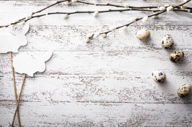 Ahşap bir arka planda Paskalya, bıldırcın yumurtası, söğüt dalları ve tavşan