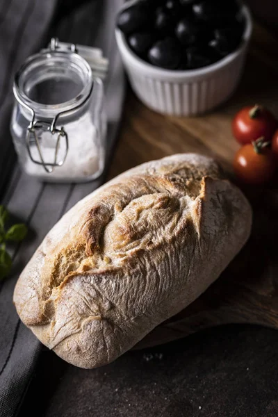 Una pagnotta fresca e saporita di pane di grano con l'aggiunta di pomodori e olive nere . — Foto Stock