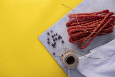 Kuru sosis. Sarı arka planda baharatlarla ince sosis
