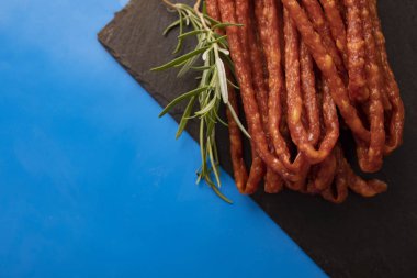 Bitkisel sosis. Mavi arka planda biberiye ile ince sosis