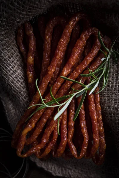 Salsichas secas de salsicha. Salsichas finas com ervas em um fundo escuro — Fotografia de Stock