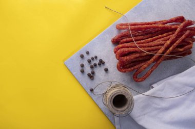 Kuru sosis. Sarı arka planda baharatlarla ince sosis