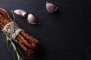 Kırsal et. Koyu bir arka plan üzerinde sarımsak ve otlar ile ince sosis