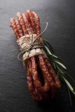 Koyu bir arka plan üzerinde otlar ile ince sosis