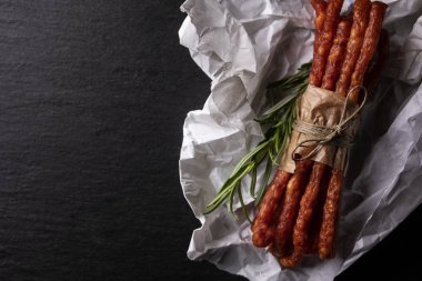 Kırsal et. Koyu bir arka plan üzerinde sarımsak ve otlar ile ince sosis