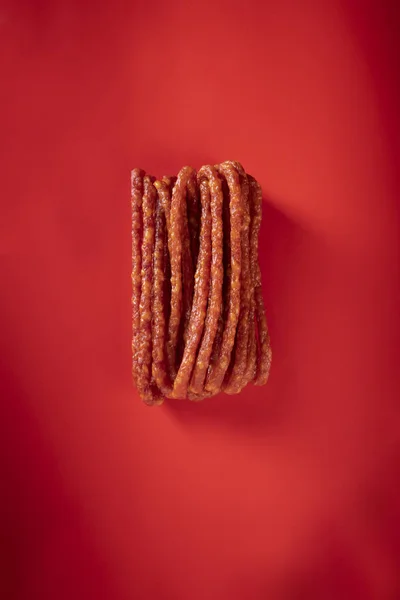 Сухі ковбаски. Тонкі ковбаски на червоному тлі — стокове фото
