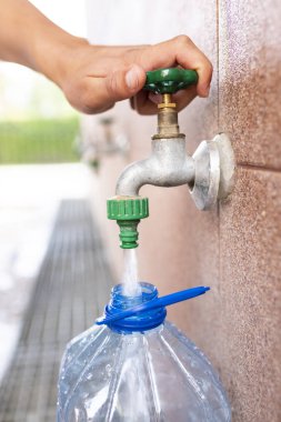 Oligosin su alımı. Temiz içme suyu. Plastik bir şişeye su dökmek.