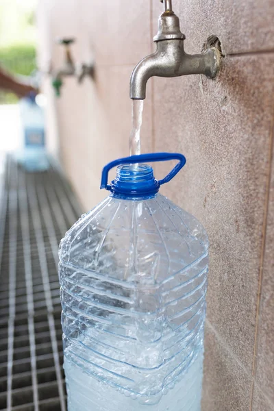 Toma de agua potable. Verter agua en una botella de plástico . — Foto de Stock