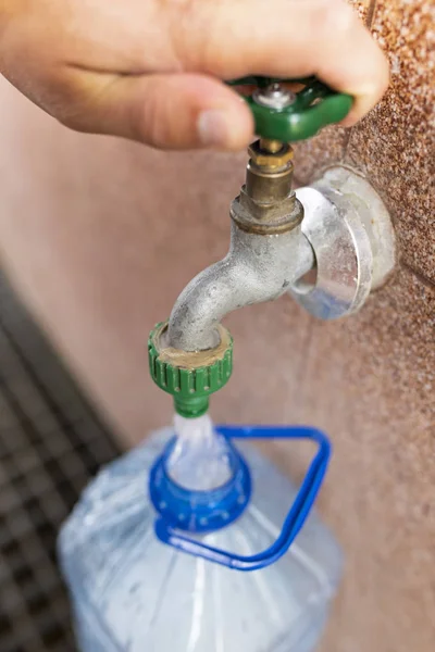 Toma de agua potable. Verter agua en una botella de plástico . — Foto de Stock