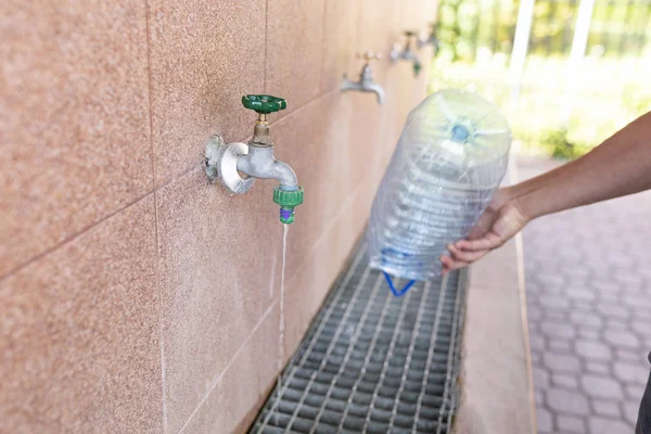 Toma de agua potable. Verter agua en una botella de plástico . — Foto de Stock