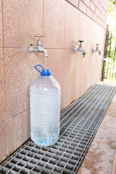 Intag av dricksvatten. Hälla vatten i en plastflaska. — Stockfoto