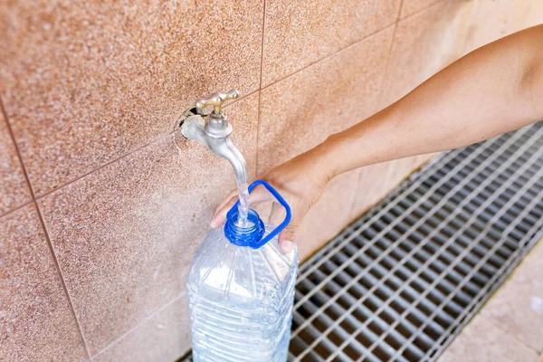 Toma de agua potable. Verter agua en una botella de plástico . — Foto de Stock