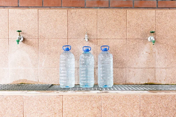 Agua de manantial. Verter agua de un pozo en una botella de plástico . — Foto de Stock