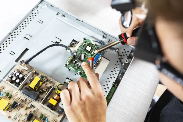 Un técnico de servicio suelda componentes. Reparación de computadoras en un servicio profesional . — Foto de Stock