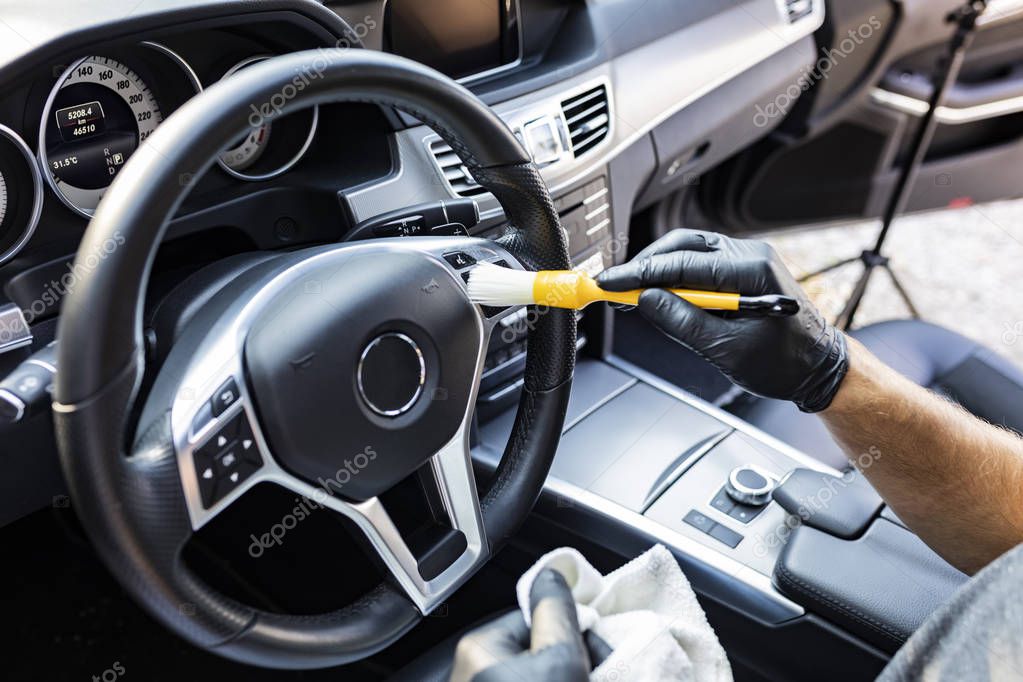 Car detailing. Vacuuming and cleaning of nooks on the dashboard and at the car steering wheel
