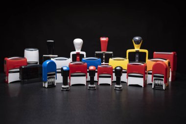 Pullar, mühürler ve tarih pulları. Siyah arkaplandaki lastik damgaların renkli mekanizmaları