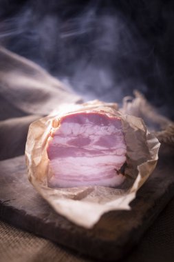 Kağıda sarılmış taze tütsülenmiş domuz pastırması. Geleneksel bir şekilde hazırlanmış salamlar..