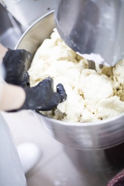 Makine hamur yoğuruyor. Aşçı yemek için malzemeleri hazırlar..