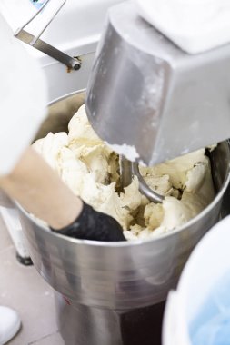 Makine hamur yoğuruyor. Aşçı yemek için malzemeleri hazırlar..