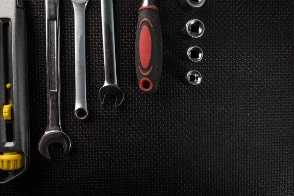 Professional set of hand tools. Utility knife, combination wrenches and a socket set with ratchet on a black background.