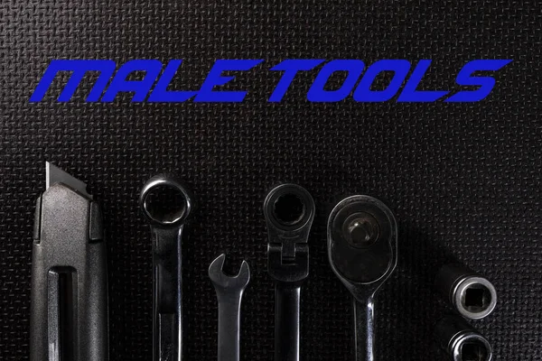 Professional hand tools set. Utility knife, combination wrenches and a socket set with ratchet on a black background.