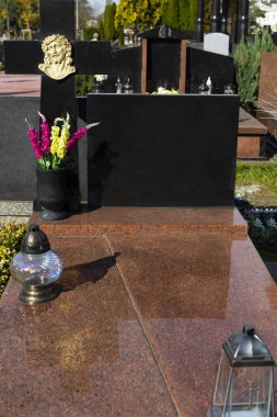 Mezar taşı. Azizler Günü 'nde mezarlığı ziyaret etmek. Granit bir mezar taşında mumlar ve çiçekler.