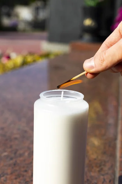 Ο άνθρωπος ανάβει ένα κερί. Γιορτή των Αγίων Πάντων. Ανάβοντας το κερί στην ταφόπλακα γρανίτη, κοντινό πλάνο. — Φωτογραφία Αρχείου