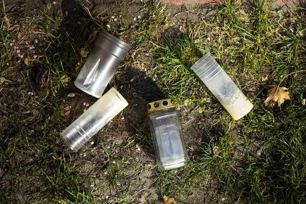 Burnt-out grave candles after All Saints Day. Empty grave lantern inserts, on a grass, on a cemetery.