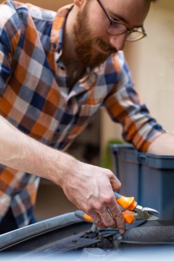 Sakallı tamirci arabaya servis yapıyor. Araba bakımı ve onarımı. 