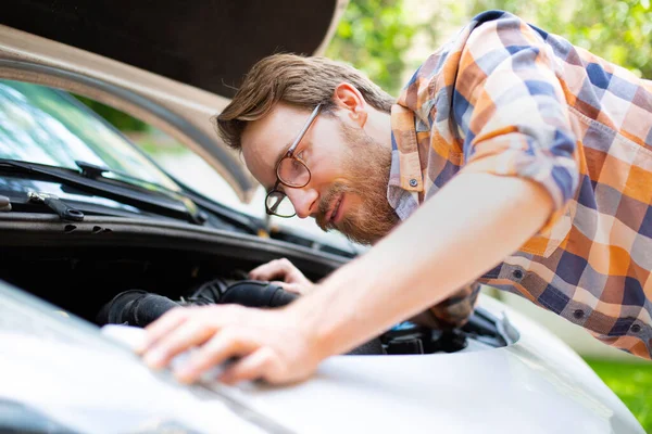 A man fixing a car on a sunny day. Self automobile repair.