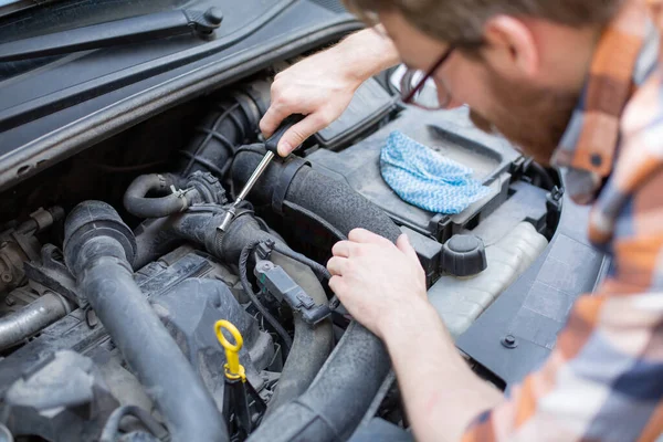 Horizontální pohled na muže, který opravuje auto šroubovákem. Samočinná oprava automobilů. — Stock fotografie