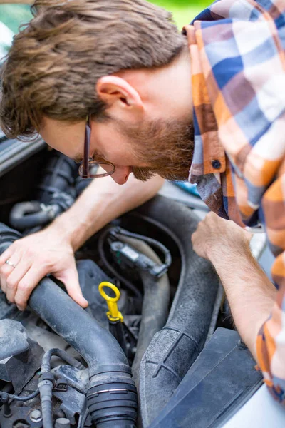 Muž, který opravuje auto za slunečného dne. Samočinná oprava automobilů. — Stock fotografie