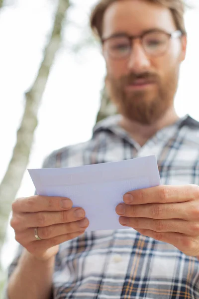 已婚男子手里拿着一封重要的信 靠得很近 专注于双手 阅读邮件 明信片 传统的邮件 邮递员查信箱的事 — 图库照片