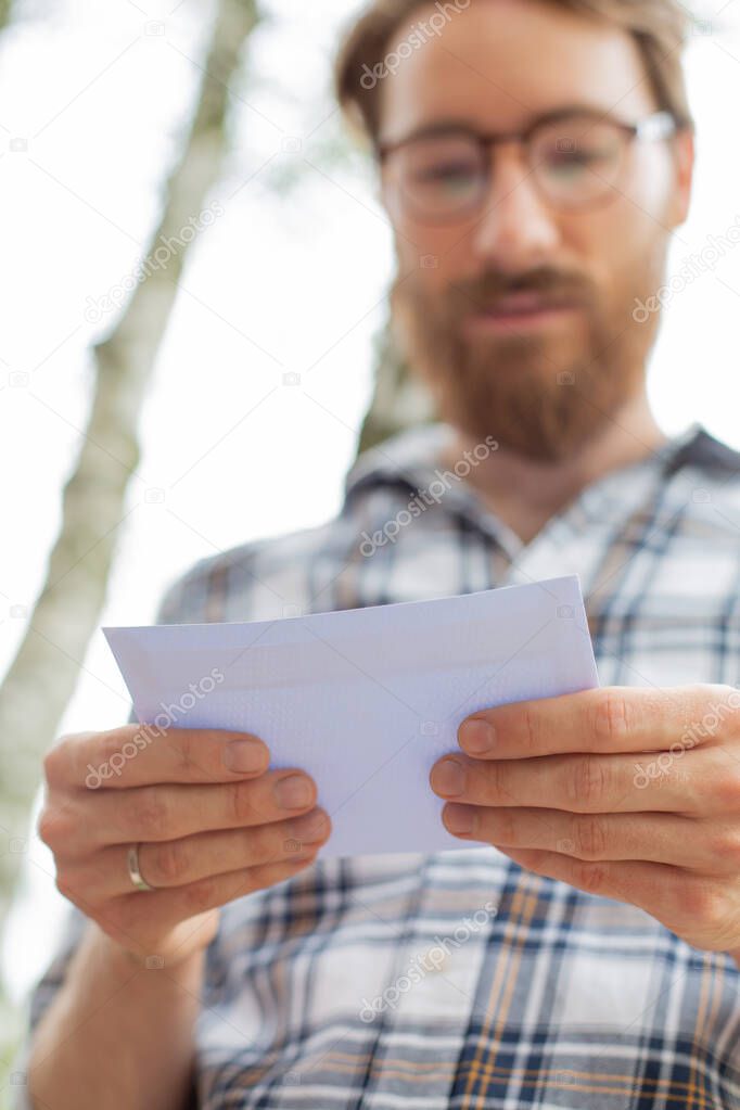 Married man holding an important letter in his hands, close up, focus on hands. Sending, receiving, reading mail, postcard, message. Traditional mail, correspondence. Postman. Checking a letterbox. 