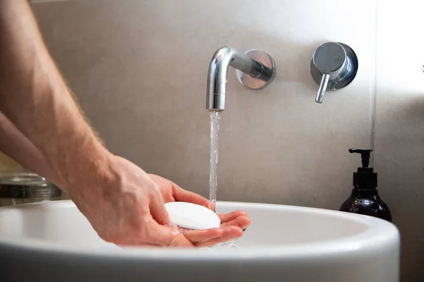 Washing hands with a soap in an elegant bathroom sink, side view. Proper cleaning hands procedure to protect infections, viruses.