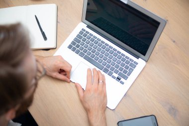 İnce dizüstü bilgisayarı ve ahşap bir masada cep telefonu olan modern ev ofisinin çalışma alanının en üst görüntüsü. Çalışmak için mobil bilgisayar kullanmak. Boş ekran ile ofis çalışma alanı kavramı, kopya hızı ile çerçeve.