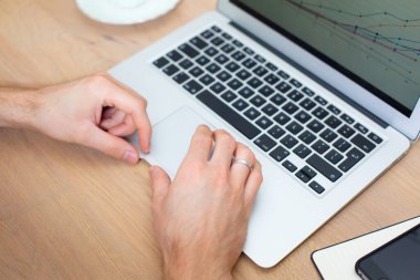 Uzaktan kumanda. Ahşap bir masada ince dizüstü bilgisayarı olan modern ofis çalışma alanı. Çalışmak için mobil bilgisayar kullanmak, sunum hazırlamak, çizelgeler. Ofis çalışma alanı kavramı, dokunmatik deftere odaklan. 