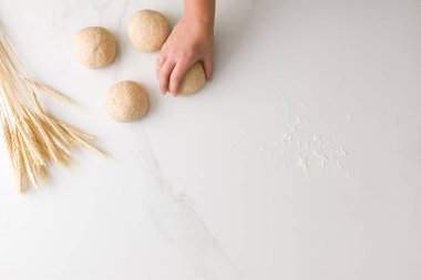 Kadın eli, üç küflenmiş ekmek hamuru, buğday ve un ile bir ekmek hamurunu metin için yer açarak alır.