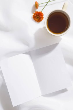 Bir kupa çay, iki portakal çiçeği ve yazı için yeri olan bir parça beyaz kağıt ile voil kumaş arka plan üst görünümü. Dikey