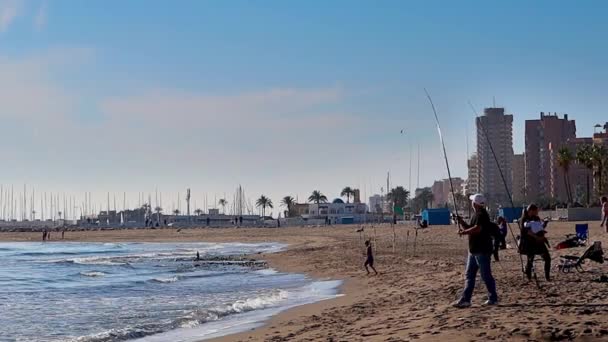 Fuengirola, Spanje-6 april 2019: een visser vissen op het strand op een winderige dag. — Stockvideo