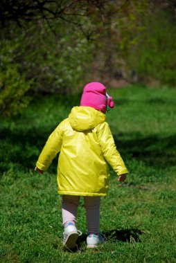 Sarı yağmurluklu bir kız ormanda yürüyor..