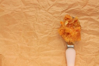 Kağıt arka planında bir kaşıkta çiğ petek kapağı