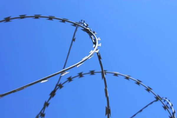 Barbed wire on fence with blue sky, the concept of prison, salvation, copy space. Stock Picture