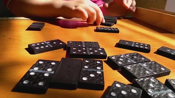 Ensinando as crianças a jogar dominó jogo em um fundo de madeira, princípio dominó, a criança está jogando . — Vídeo de Stock