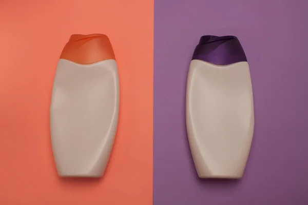 Beauty, decorative cosmetics bottles. Peach and purple colors background, flat lay, top view, minimalistic pop-art style