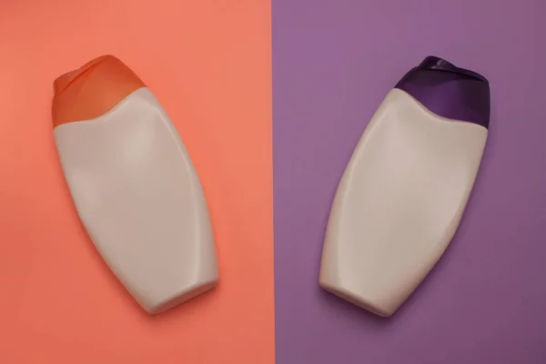Beauty, decorative cosmetics bottles. Peach and purple colors background, flat lay, top view, minimalistic pop-art style
