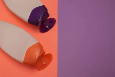 Güzellik, dekoratif kozmetik şişeleri. Şeftali ve mor renkler arka plan, düz yatıyordu, üst görünüm, minimalist pop-art tarzı