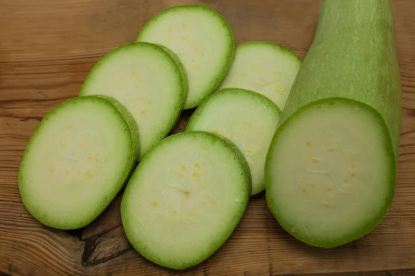 Sliced green zucchini on wooden background, copy space. Healthy food, green vegan diet, raw recipes.